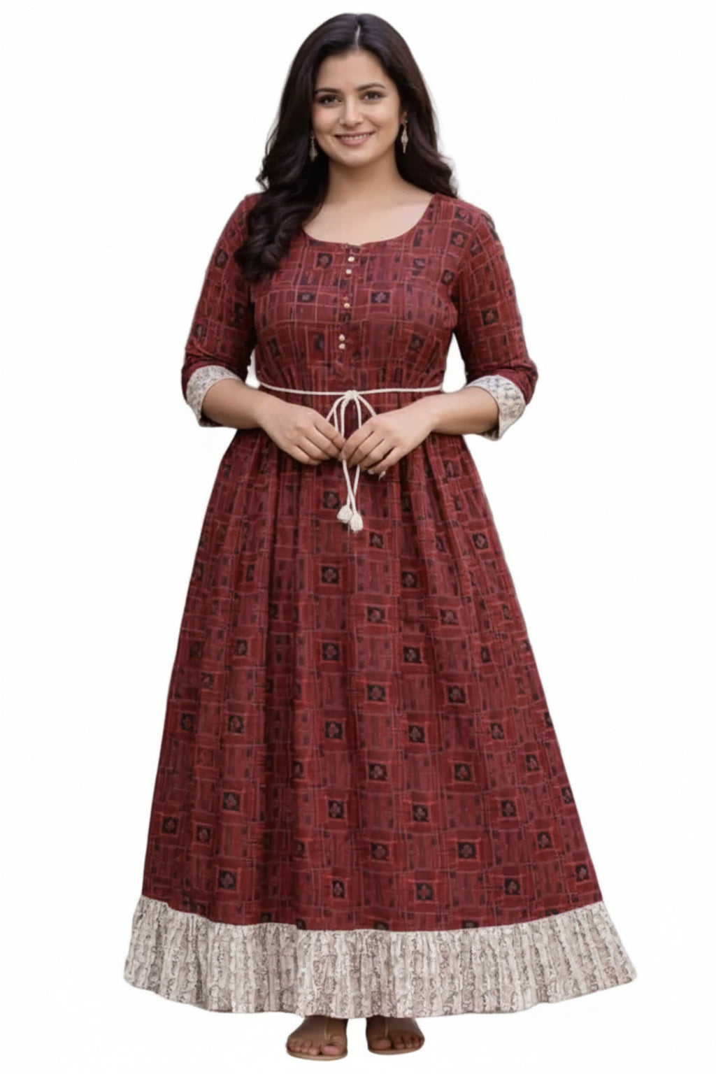 Woman wearing a red patterned dress standing outdoors on a path with greenery.