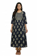 Woman wearing a navy blue floral dress with intricate patterns on a plain background