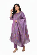 Woman wearing a purple embroidered outfit with a dupatta, standing against a light background.