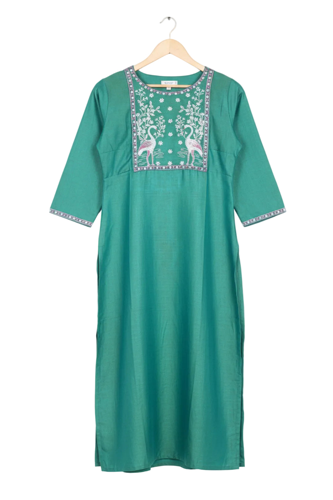 Green embroidered kurta with white pants worn by a model on a pink background