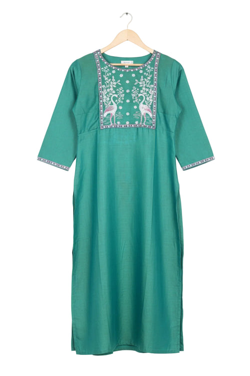 Green embroidered kurta with white pants worn by a model on a pink background