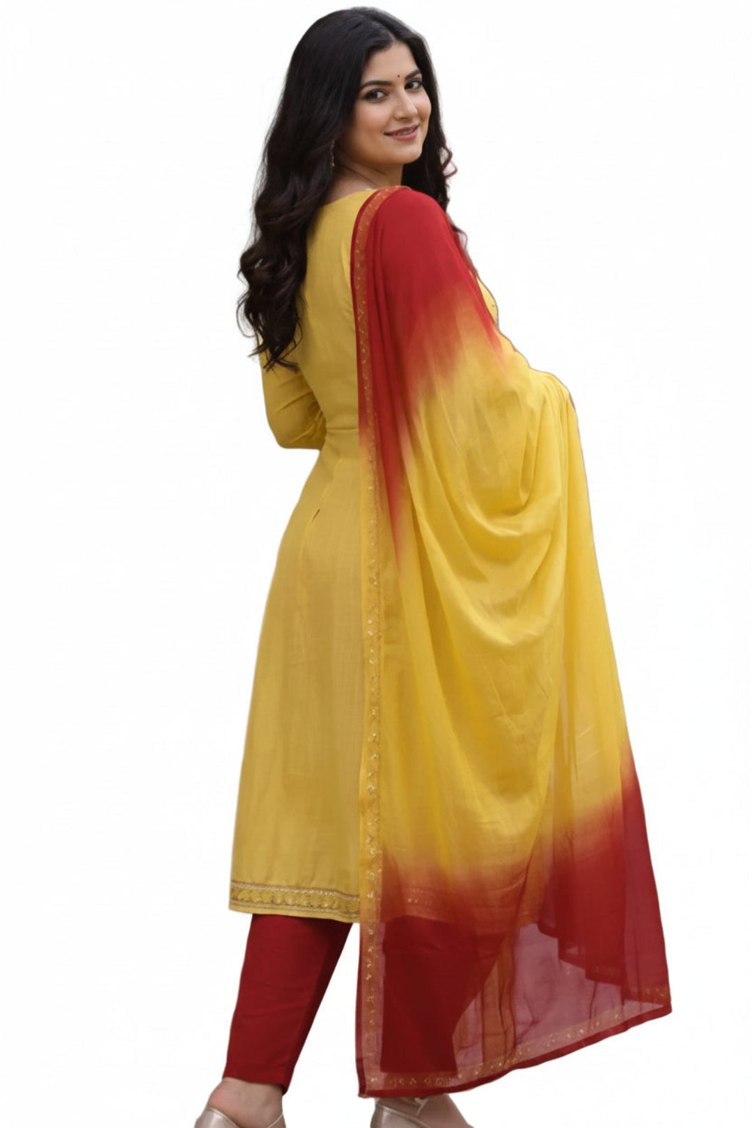 Woman wearing a yellow and red traditional outfit standing outdoors on a path.